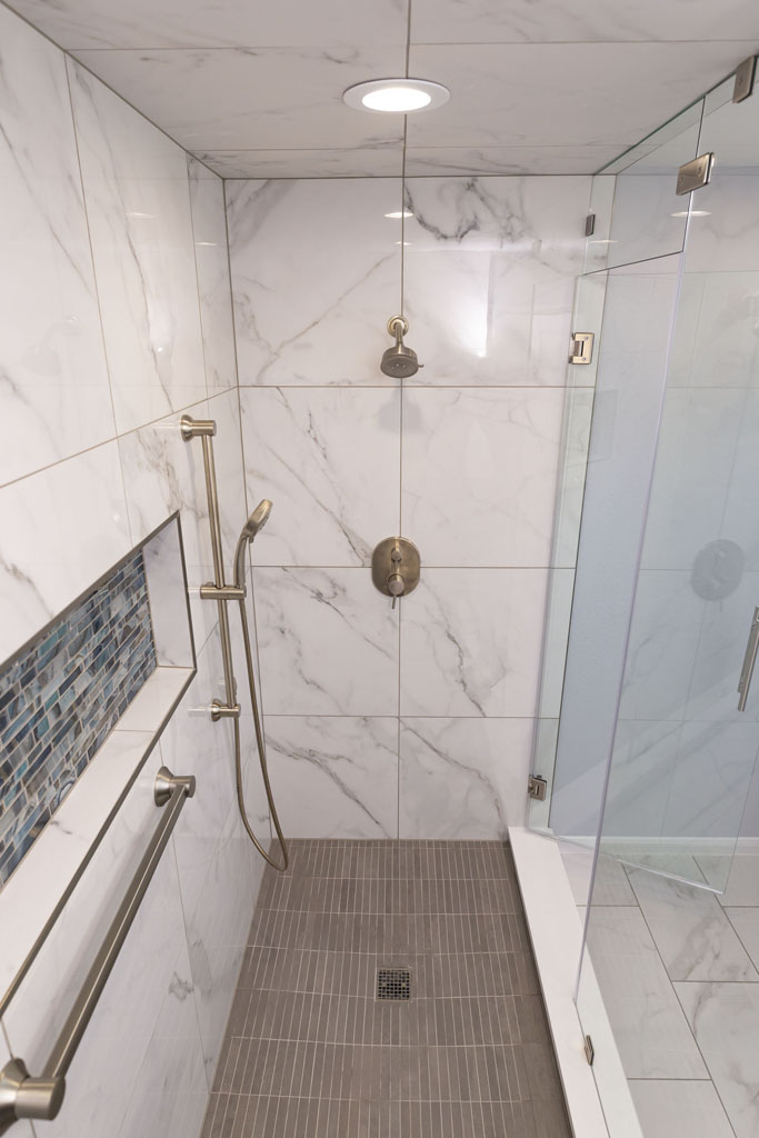 Interior image of a remodeled bathroom with stand in shower and frameless glass shower door.