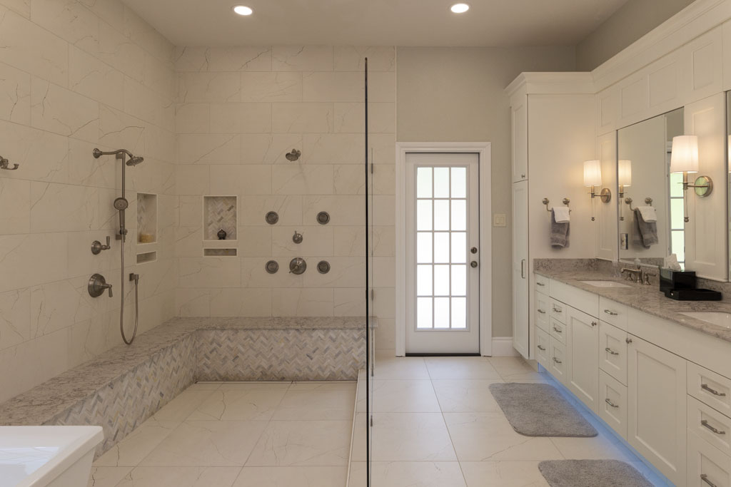 Large bathroom renovation with a double sink vanity and stand in shower with a frameless shower wall